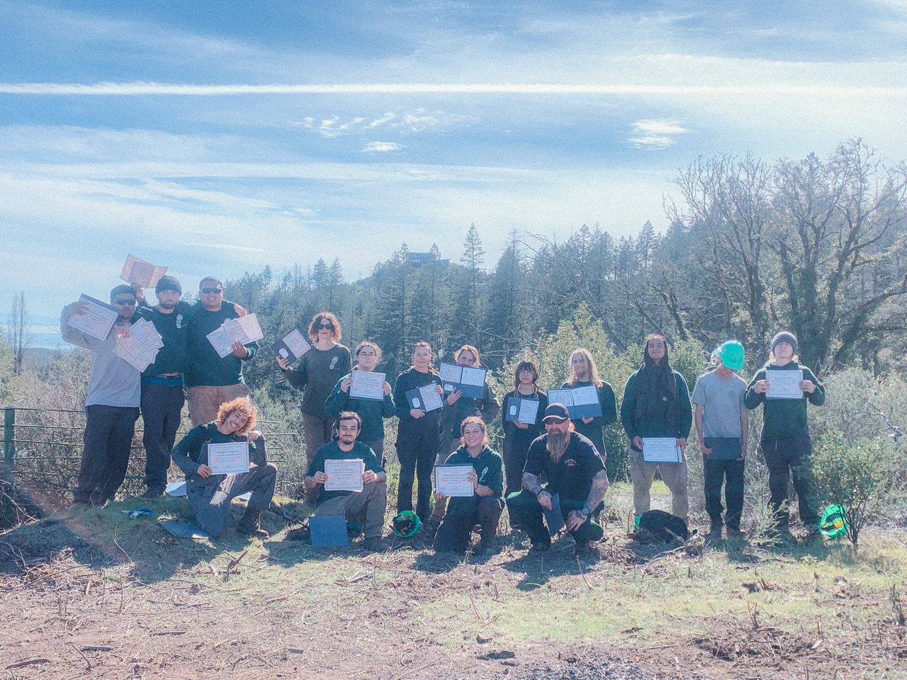 A conservation corps cohort holding the certificates they earned, at the end of a program.